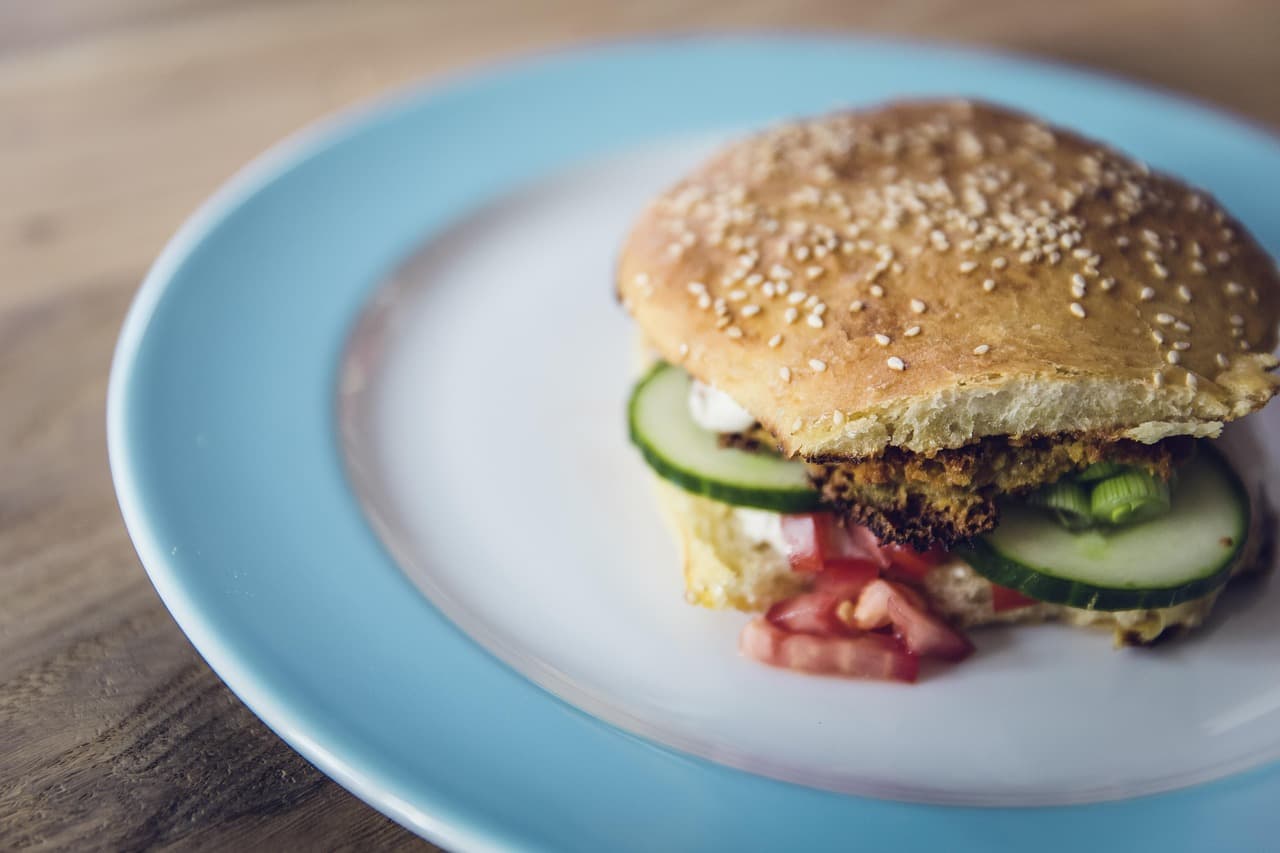 A veggie burger with cucumber and salad in a sesame bun