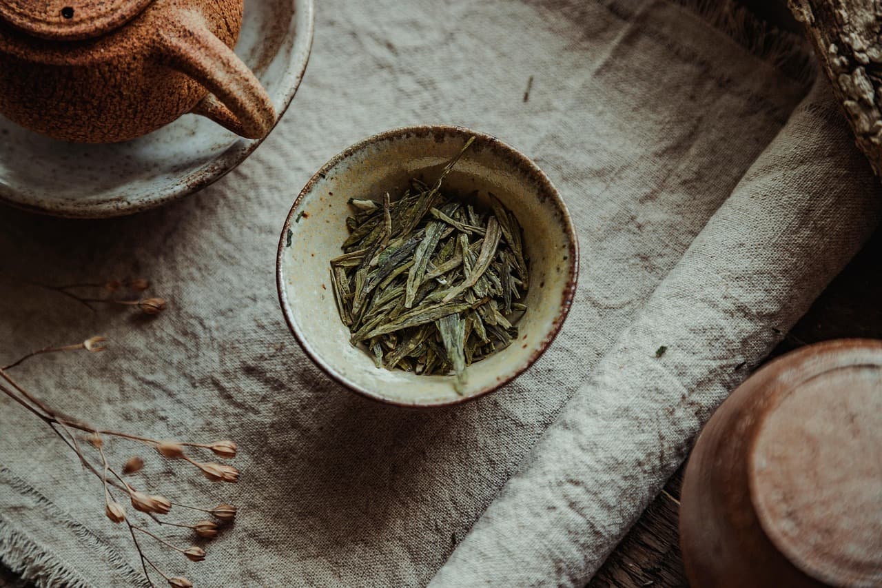 Loose-leaf tea in a small bowl beside a teapot