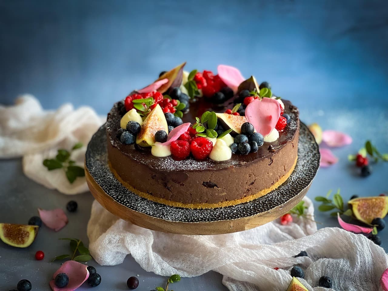 A chocolate cake topped with berries and edible flowers
